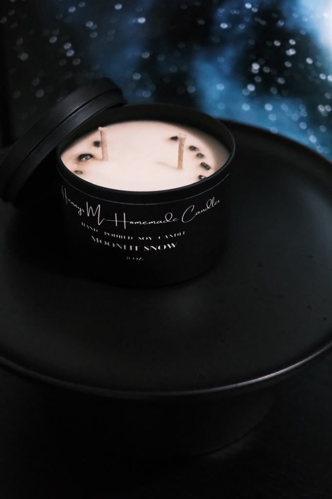 Moonlit Snow candle open on a dark surface beneath a field of stars